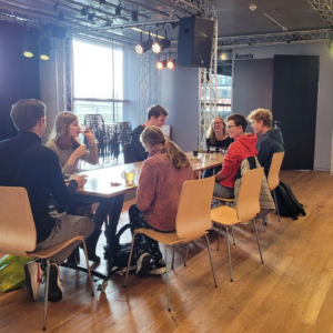 Leden van Club Orange aan een tafel in het Muziekgebouw aan 't IJ te Amsterdam