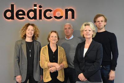 De leden van de Raad van Toezicht poseren voor lichtgevende letters Dedicon