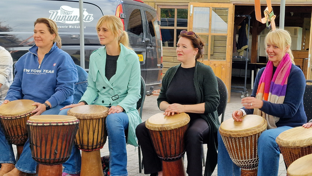 Vier collega's tijdens de workshop djembé.