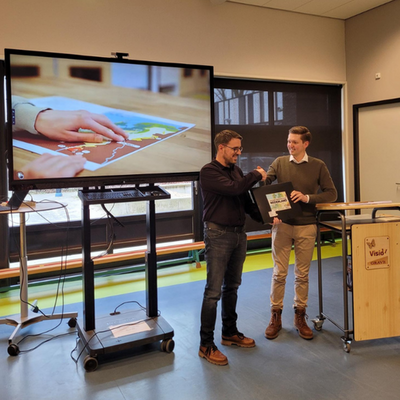 Productmanager Julian Nauta overhandigt de eerste Voelbare Tekening Atlas aan docent Jurgen van den Broek